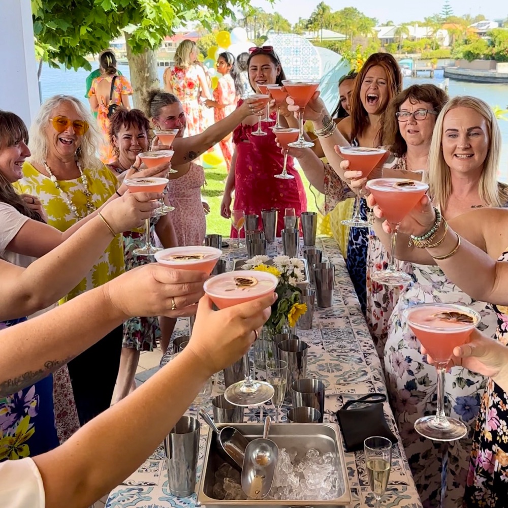 A group cheering with pink cocktails in a garden
