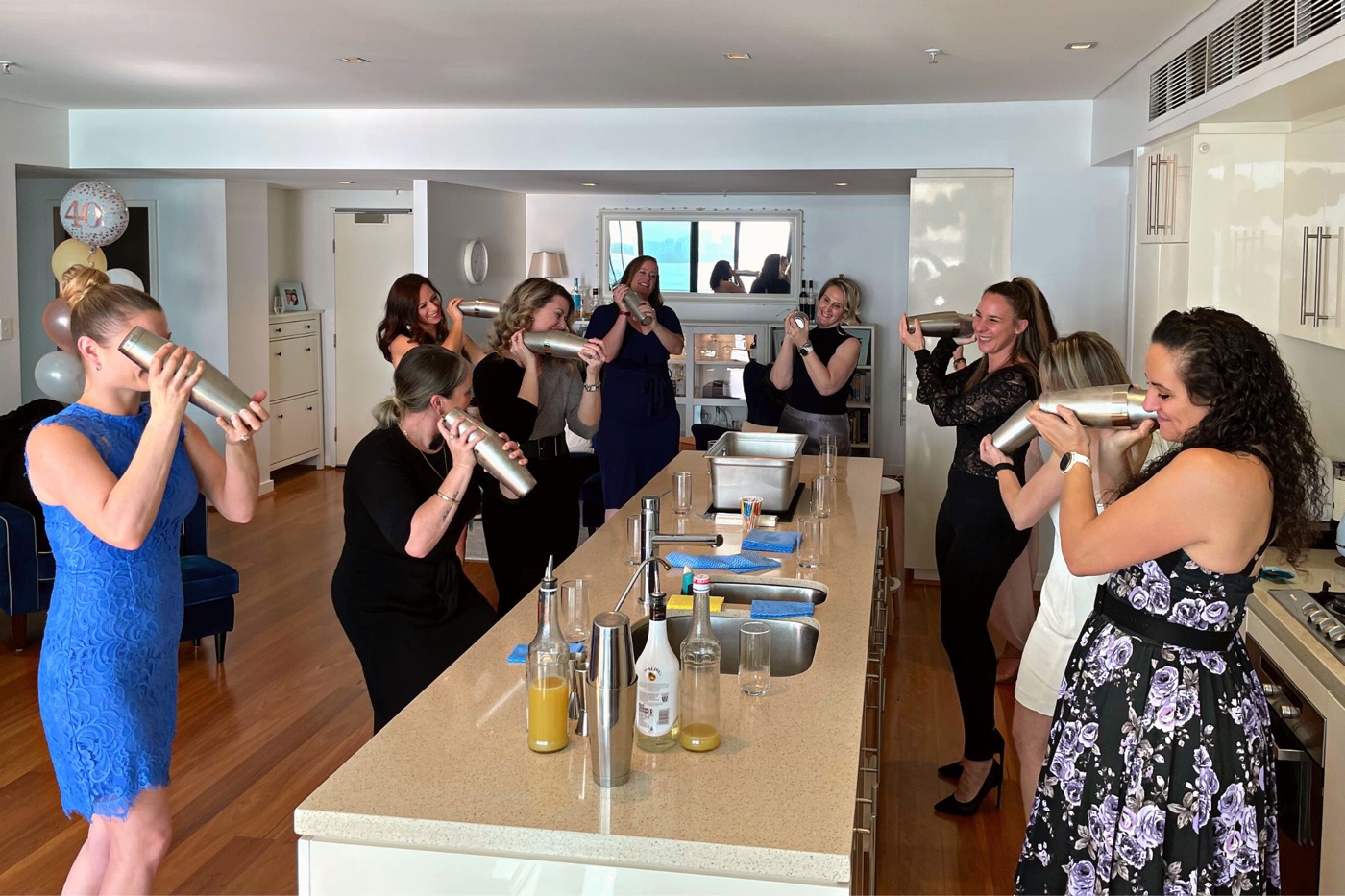 Guests shaking cocktails together in a home kitchen