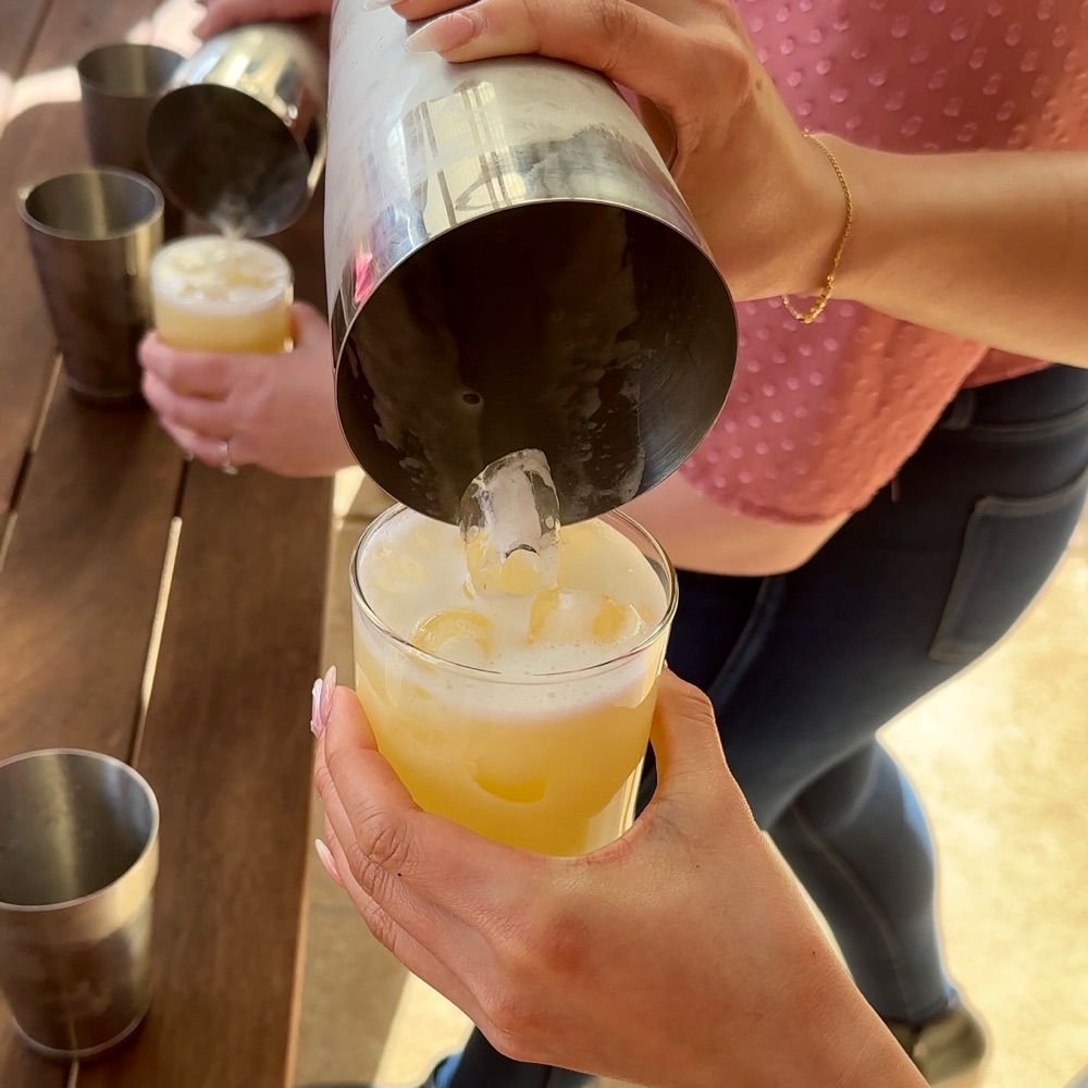 A guest pouring a cocktail from a shaker into a glass