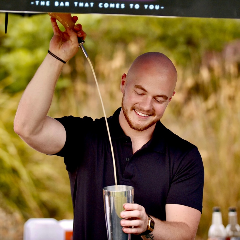 Scott smiling as he pours a cocktail from a height